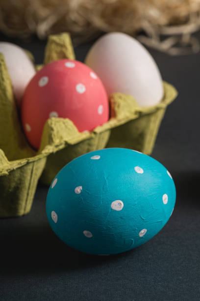 istock Colorful polka dot Easter eggs in egg tray on dark grey black plain background, greeting card, macro angle view 1210944933
