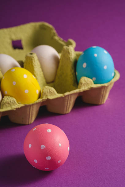 istock Colorful polka dot Easter eggs in egg tray on purple violet plain background, greeting card, copy space, macro angle view 1210944947