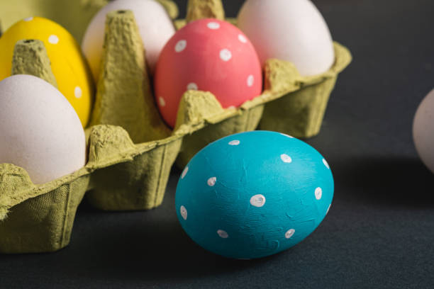 istock Colorful polka dot Easter eggs in egg tray on dark grey black plain background, greeting card, macro angle view 1210944989