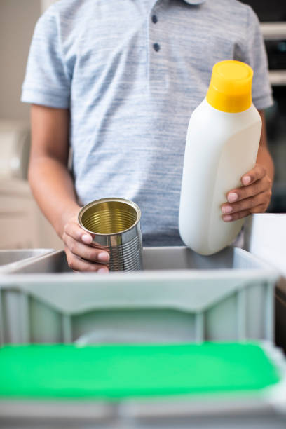 Close Up Of Boy Sorting Recycling Into Kitchen Bin At Home