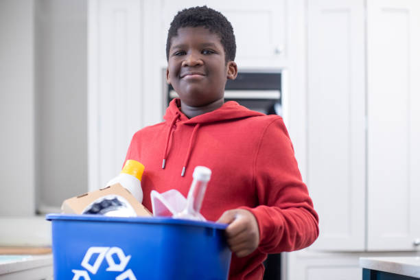 retrato de niño de pie en la cocina en casa llevando la papelera de reciclaje - recycling recycling symbol environmentalist people fotografías e imágenes de stock