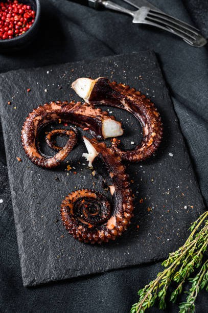 istock Grilled octopus tentacles. Fresh seafood. Black background. Top view 1210947503