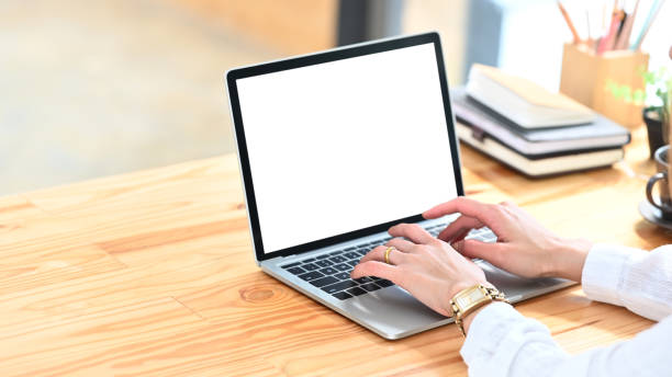 istock Cropped image of secretary hands while typing on computer laptop with white blank screen at the modern working desk with comfortable/orderly office as background. 1210948317