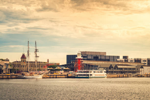 Port Adelaide, Australia - December 8, 2018: Iconic Port Adelaide lighthouse with Dolphin Explorer boat viewed across Port River at sunset