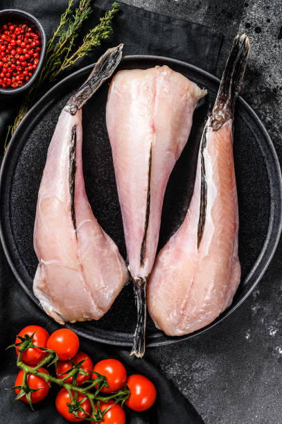 istock Separate raw fish monkfish. Black background. Top view 1210948516