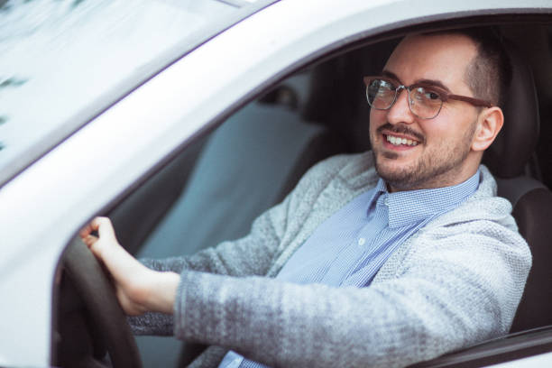 istock Attractive happy young man driving car and smiling 1210949692