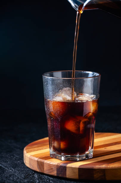 istock Iced Cola or Cold Coffee Pouring into Tall Glass on Dark Background. Concept Refreshing Summer Drink 1210960362