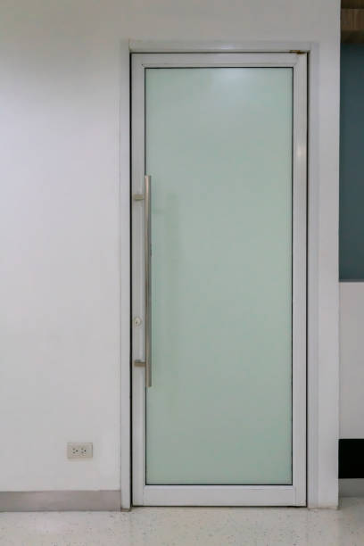 istock Narrow and tall glass door on white wall. Interior design. 1210961786