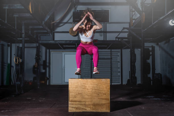 Young strong sweaty fit muscular girl with big muscles doing box jump hardcore cross workout training in the gym selective focus motion blur real people exercise Young strong sweaty fit muscular girl with big muscles doing box jump hardcore cross workout training in the gym selective focus motion blur real people exercise extreme dedication stock pictures, royalty-free photos & images