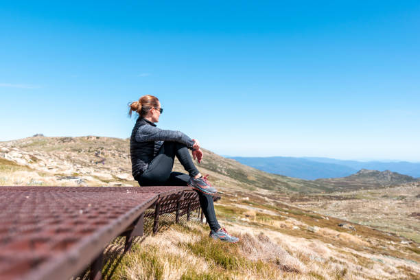 спортивная молодая женщина-туристка, отдыхающая на ржавой стальной набережной возле вершины го�ры костюшко (2228 м над уровнем моря) национал� - kosciuszko national park стоковые фото и изображения