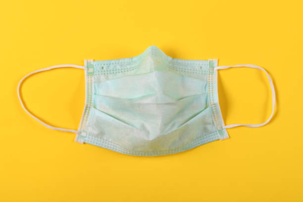 istock medical face mask on a yellow background 1210964396
