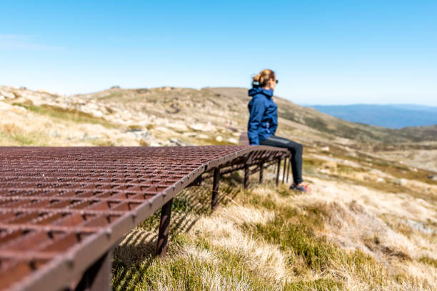 спортивная молодая женщина-туристка, отдыхающая на ржавой стальной набережной возле вершины горы костюшко (2228 м над уровнем моря) национал� - kosciuszko national park стоковые фото и изображения