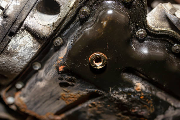 screwed bolt at the bottom of the oil pan of a diesel engine with a new, copper washer, after pouring out old oil. - copper pan at the bottom of old imagens e fotografias de stock