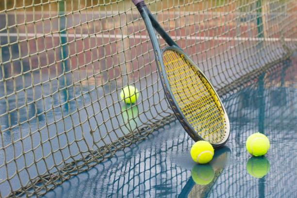 istock Racket and wet tennis balls on court covered with rain 1210972772