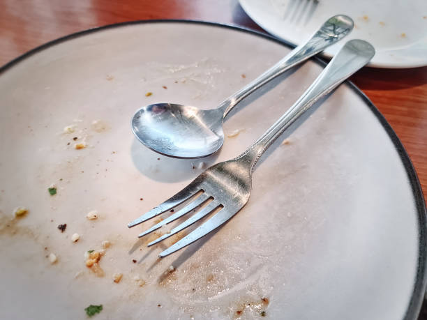 istock Fork and Spoon on White Plate with Food Leftovers After the Meal 1210975962
