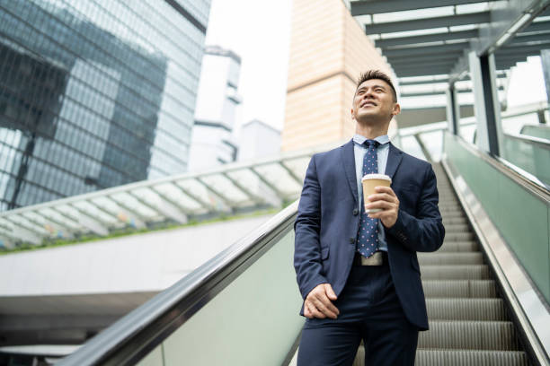 istock Businessman holding coffee cup and moving up on escalator 1210976673