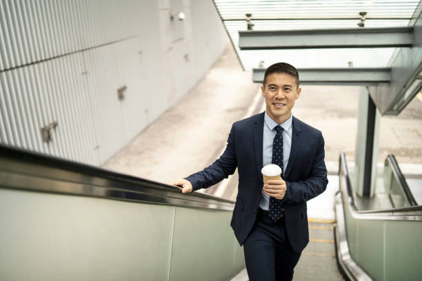 istock Businessman holding coffee cup and moving up on escalator 1210976678