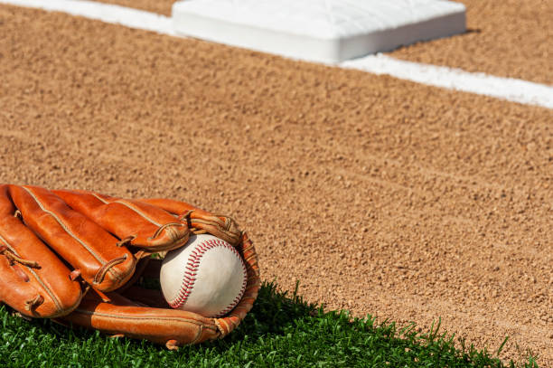 una pelota de béisbol en un guante a lo largo de la línea de base del infield de un diamante de béisbol - baseball diamond baseball baseline grass fotografías e imágenes de stock