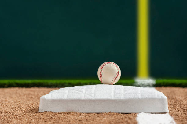 una pelota de béisbol sentada en la parte superior de la primera base mirando hacia abajo las líneas de foul - baseball diamond baseball baseline grass fotografías e imágenes de stock