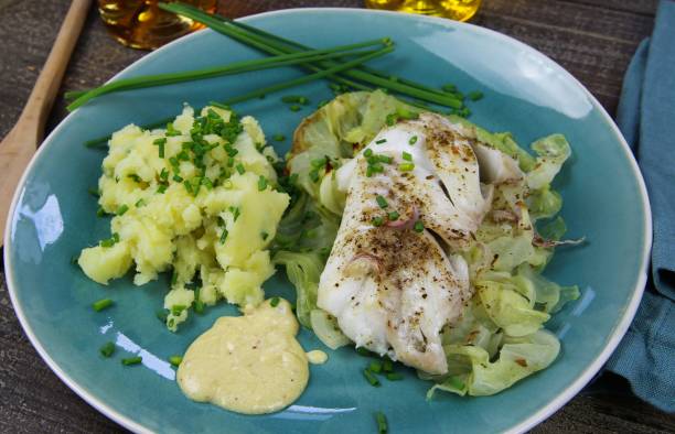 istock Isolated blue china dish with codfish fillet poached on pointed cabbage, mustard sauce and mashed potatoes seasoned with chives 1210980201