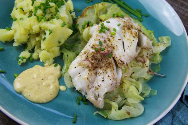 istock Isolated blue china dish with codfish fillet poached on pointed cabbage, mustard sauce and mashed potatoes seasoned with chives 1210980206