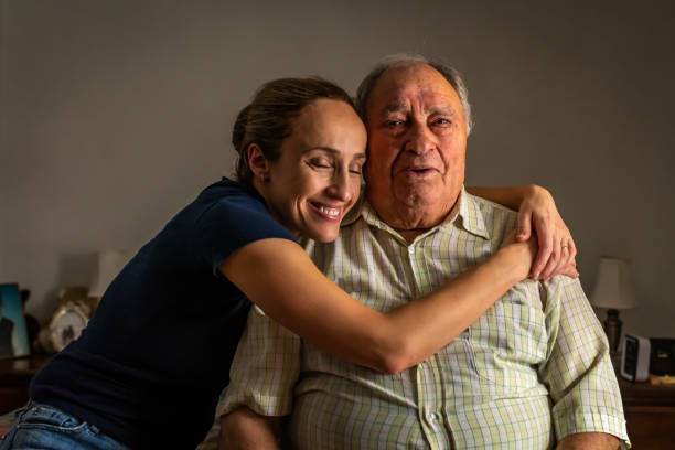 Portrait of an old Portuguese man with his daughter. Portrait of a daughter holding her elderly father, sitting on a bed by a window in her father's room. pudgy woman pictures stock pictures, royalty-free photos & images