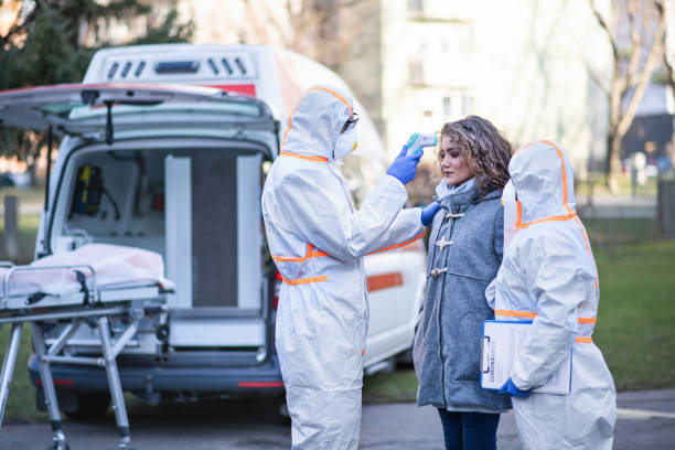istock People with protective suits helping woman outdoors, coronavirus concept. 1210983244