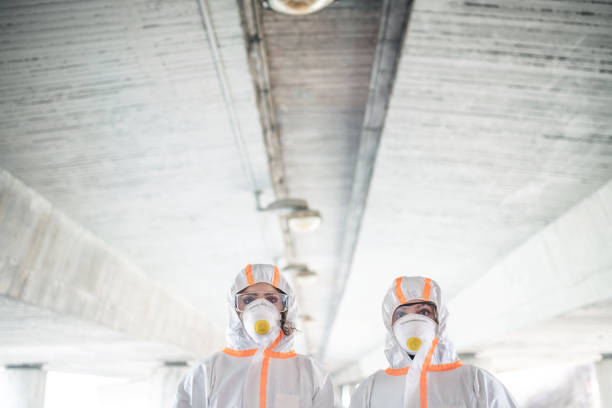 istock People with protective suits and respirators standing outdoors, coronavirus concept. 1210983257