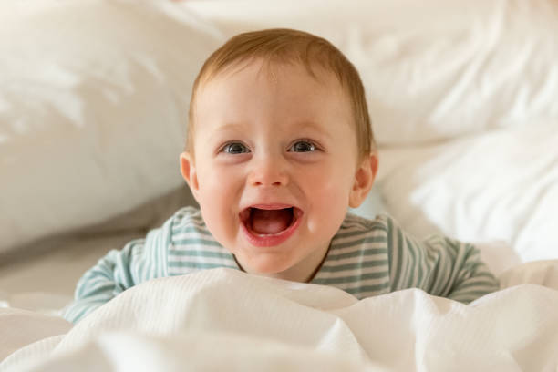 istock Baby boy 8 months old smiling whilst lying on bed with white bedding 1210983646