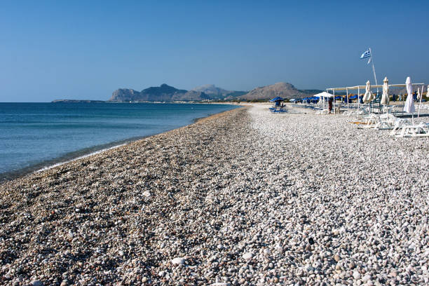 parasole plażowe na kamiennym wybrzeżu wyspy rodos - pebble bed zdjęcia i obrazy z banku zdjęć