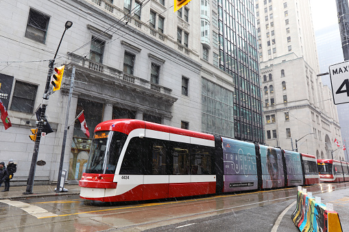 February 26, 2020 - Toronto, Ontario, Canada: Downtown Toronto (King and Yonge Street Intersection) on a snowy day in February and red TTC Streetcar (made by Bombardier). Symbols of Toronto - skyscrapers and TTC car (Toronto tram). Transportation in Toronto, Canada. Morning in Toronto, Canada. Toronto Transit Commission streetcar in the financial district of Toronto, Canada.