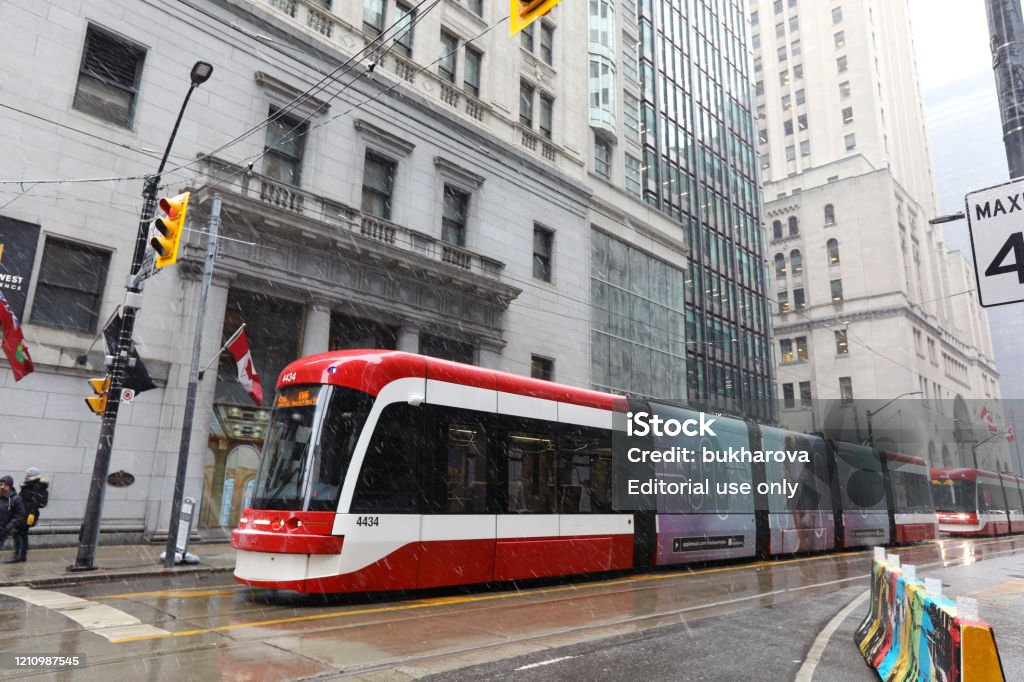 Downtown Toronto and TTC Streetcar February 26, 2020 - Toronto, Ontario, Canada: Downtown Toronto (King and Yonge Street Intersection) on a snowy day in February and red TTC Streetcar (made by Bombardier). Symbols of Toronto - skyscrapers and TTC car (Toronto tram). Transportation in Toronto, Canada. Morning in Toronto, Canada. Toronto Transit Commission streetcar in the financial district of Toronto, Canada. Toronto Stock Photo