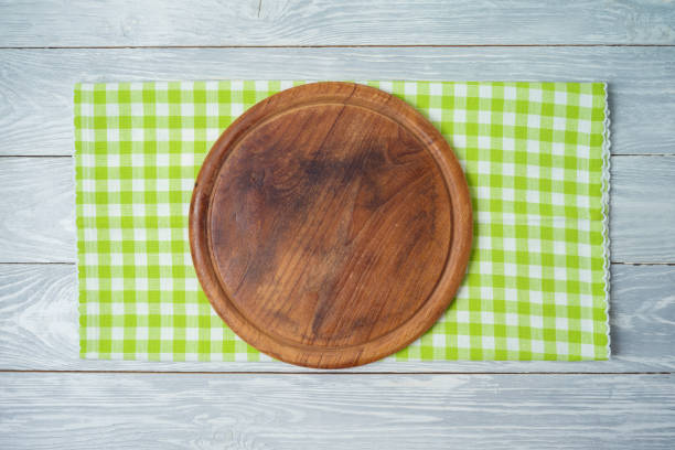 istock Round pizza board with green checked tablecloth on rustic wooden table 1210991665