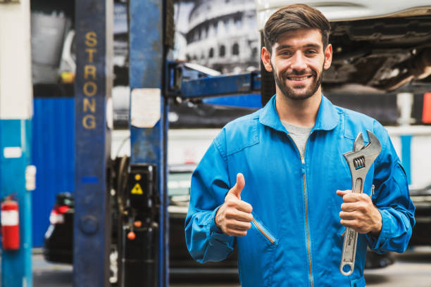 mechanic standing, thumbs up and hold a wrench with blur garage in the background. auto car repair service center. professional service. - thumbs up business occupation competition imagens e fotografias de stock