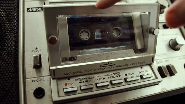 The old cassette player inserts a cassette into the boombox. Retro cassette player concept.