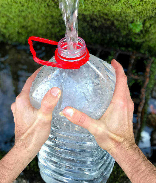 istock Man`s hand holding plastic water bottle  and collect fresh water from spring. 1210998505