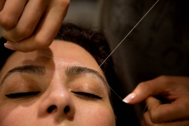 Eyebrow threading macro Professional eyebrow hair removal service on a woman in a hair salon. hair threading stock pictures, royalty-free photos & images