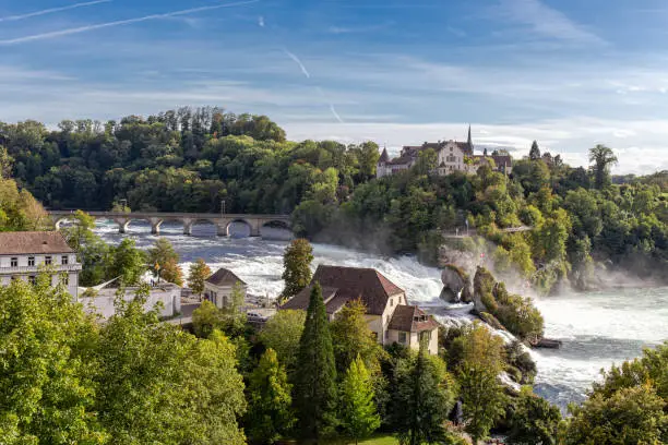 Rheinfall the large and powerful waterfall surround with green forest and blue sky background view from Neuhausen am Rheinfall railway station in switzerland