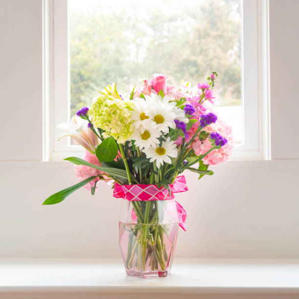 istock Beautiful spring flowers bouquet in vase on white window bench 1211002906