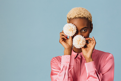 Portrait of a beautiful young woman holding two white pink flowers