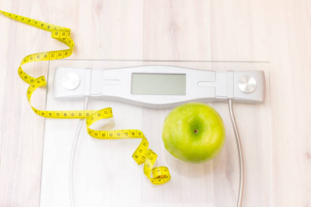 Green apple with a measuring tape and dumbbells.