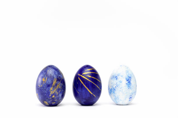 istock Three easter eggs trendy colored classic blue, white and golden decorated on white table. Happy Easter card with copy space for text. Minimal style 1211013390