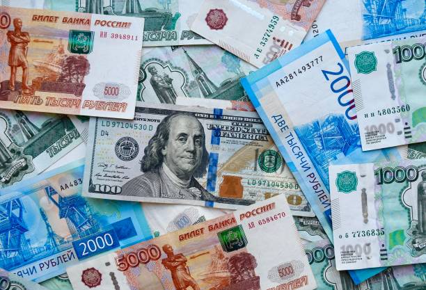 US dollar banknote on top of russian national currency, top view of mixed rouble banknotes stock photo