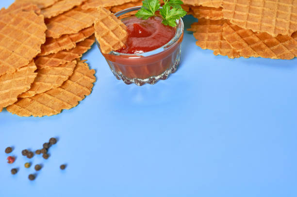 istock Many thin spicy waffles, savory sauce, scattered pepper on purple background. Space for text 1211020407