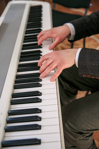 istock Hands behind the keys of a white synthesizer. Sharpness in the foreground. 1211025038