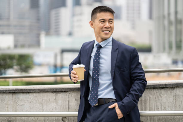 istock Businessman walking in park and holding coffee cup 1211025120