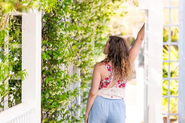 Photo of Young adult woman girl person in summer on sunny day in garden vine plant flowers outside gardening and wearing pastel fashion