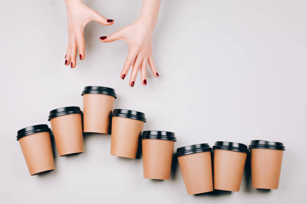 Concept of coffee addiction Beautiful hands follow to cardboard cups on pastel background. Concept of coffee addiction. Flat lay style. coffee addict stock pictures, royalty-free photos & images