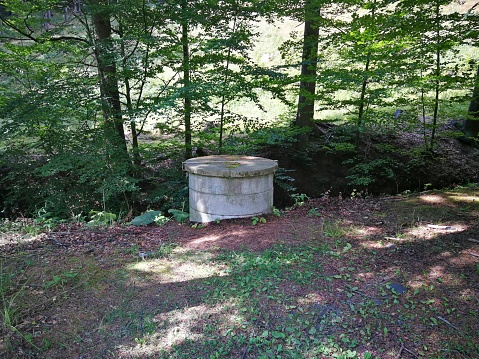 A well made of concrete rings built in the forest, image