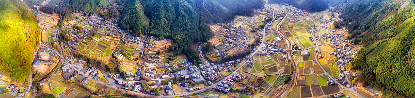 Mountain valley in Japan near Kyoto - Ohara area. Agriculture rice terraces and local farms in aerial wide panorama.